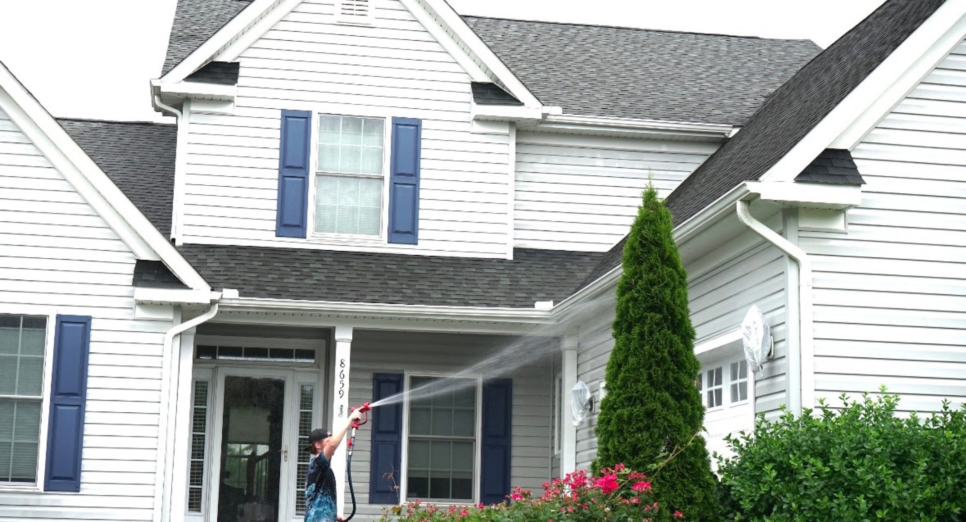 Coastal Shine technician pressure-washing white house siding with blue shutters in Easton MD on Maryland's Eastern Shore