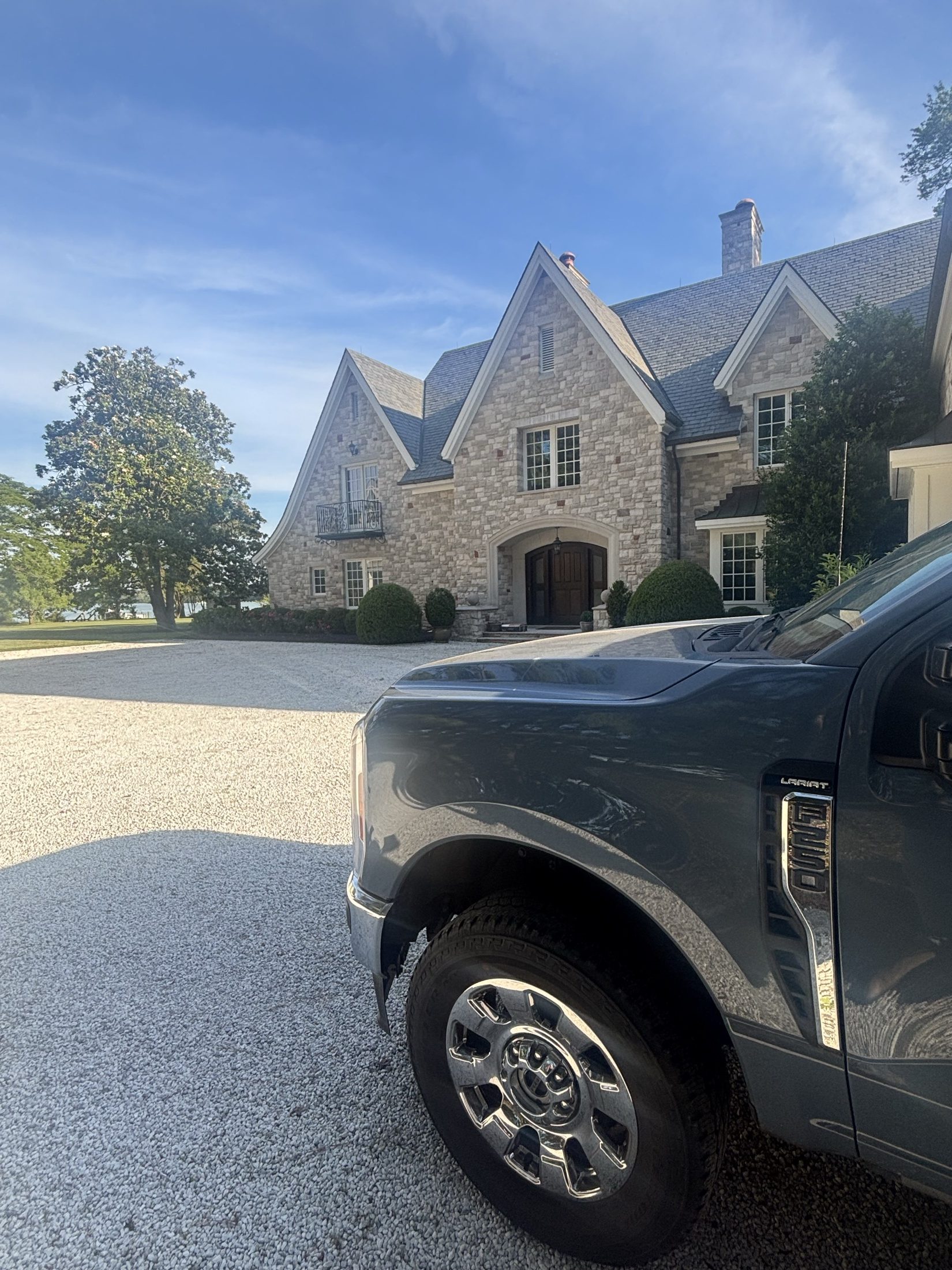 Coastal Shine work truck parked in front of a beautiful stone estate following a premium house washing service.
