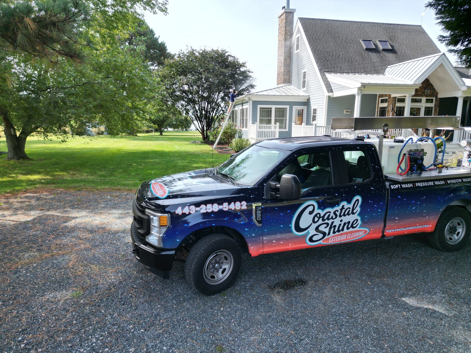 The Coastal Shine truck parked at a house wash on the Eastern Shore while a technician soft washes the siding